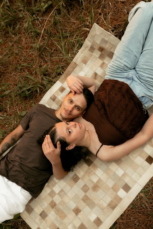 Free A couple lying close together on a blanket outdoors, showcasing intimacy and relaxation. Stock Photo