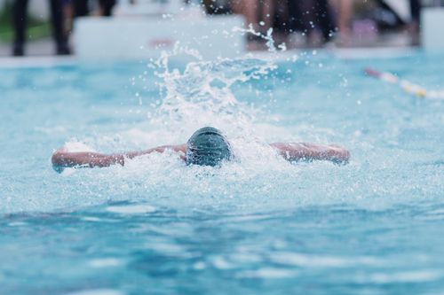 Free Male swimmer performing freestyle in an outdoor pool in Jakarta, Indonesia, creating splashes as he swims forward. Stock Photo