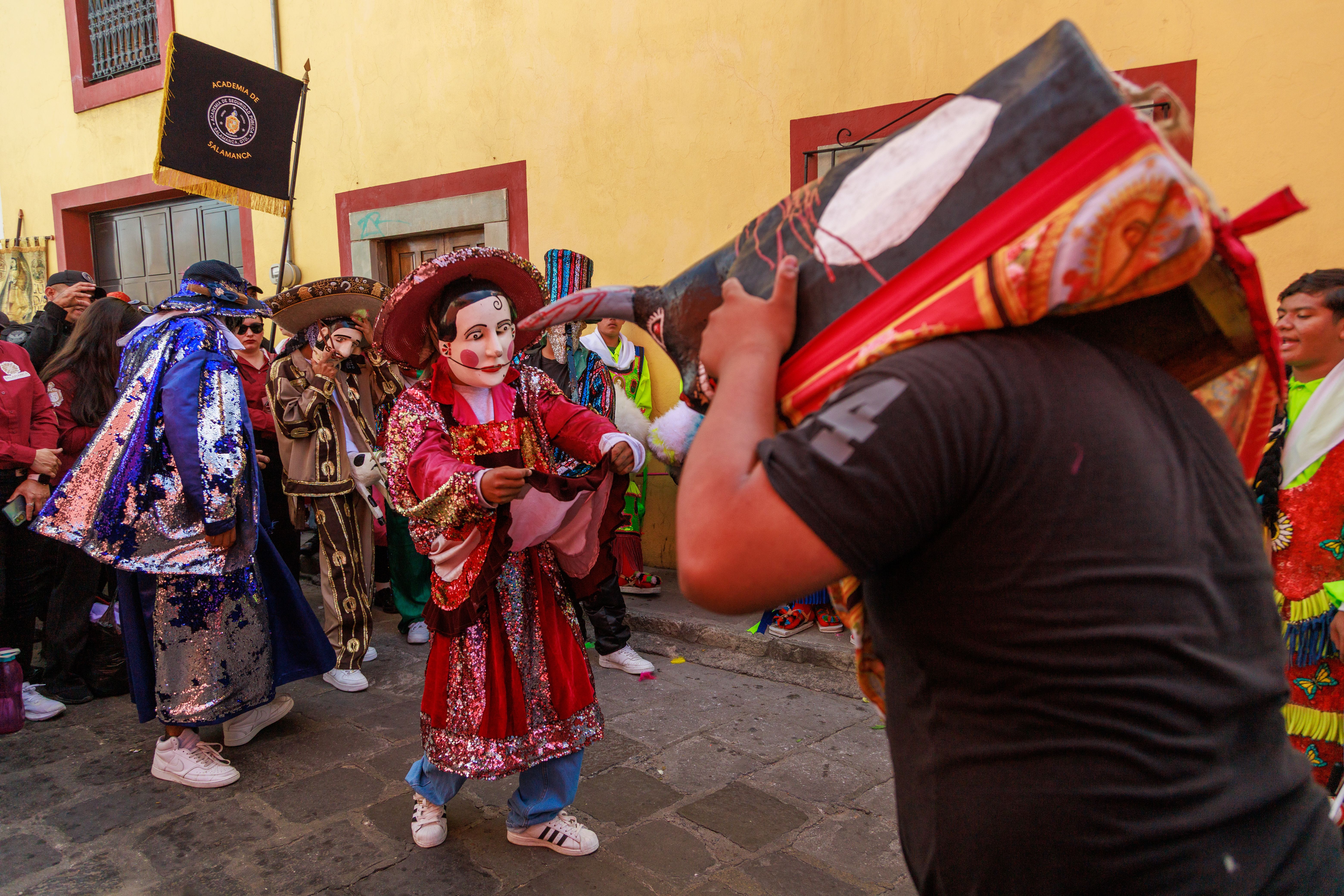 Vibrant parade featuring masked dancers in colorful costumes during a traditional Mexican festival.