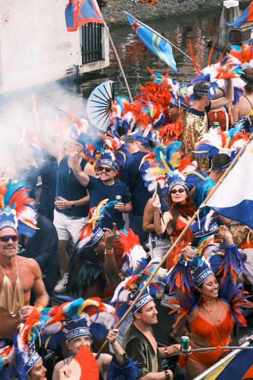 Free Colorful crowd in feather costumes celebrating canal parade in Amsterdam. Stock Photo