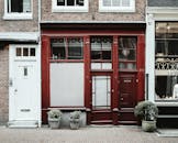 一条安静的城市街道上，有一扇迷人的红砖门面，旁边摆放着盆栽植物