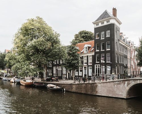 Free Scenic view of Amsterdam canal with historic houses and boats. Stock Photo