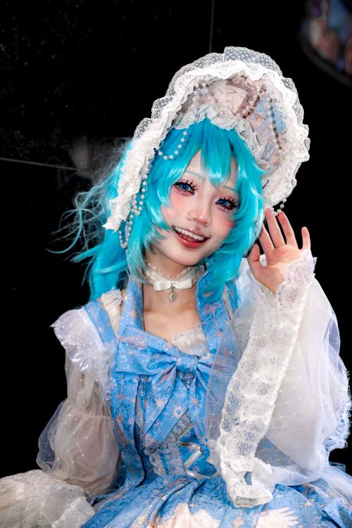 Free Colorful cosplay portrait of an adult with blue wig and lace costume, smiling and waving. Stock Photo