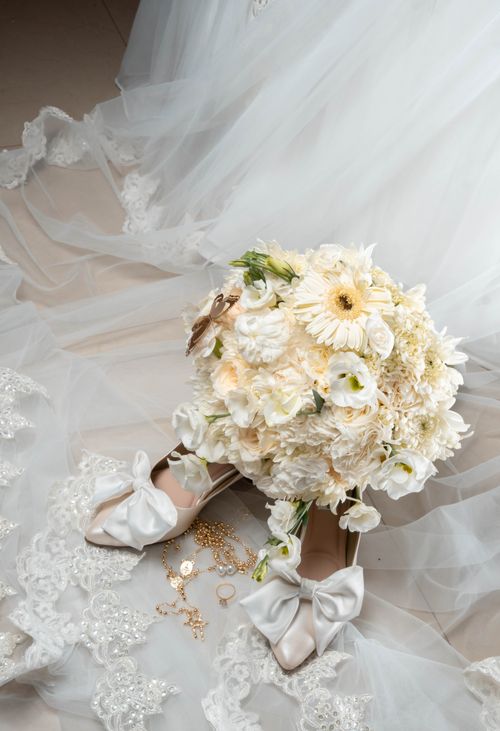 Free A close-up of wedding accessories including a bridal bouquet, shoes, and jewelry on lace fabric. Stock Photo