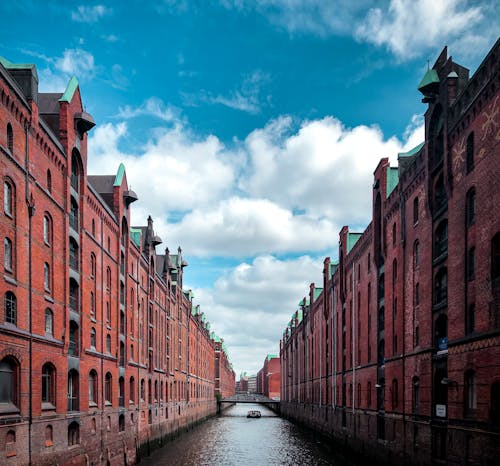 Brown Concrete Buildings Beside River Under Blue Sky