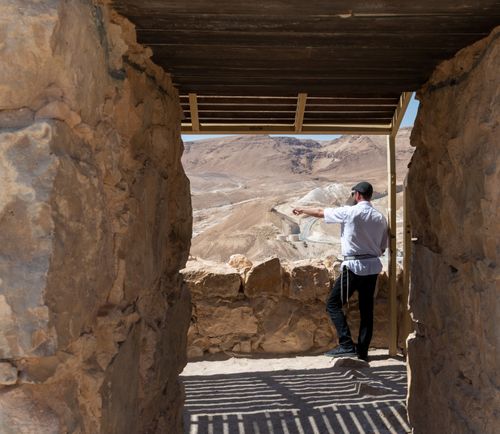 Free A person pointing at a vast desert view from an ancient stone structure, possibly Masada. Stock Photo