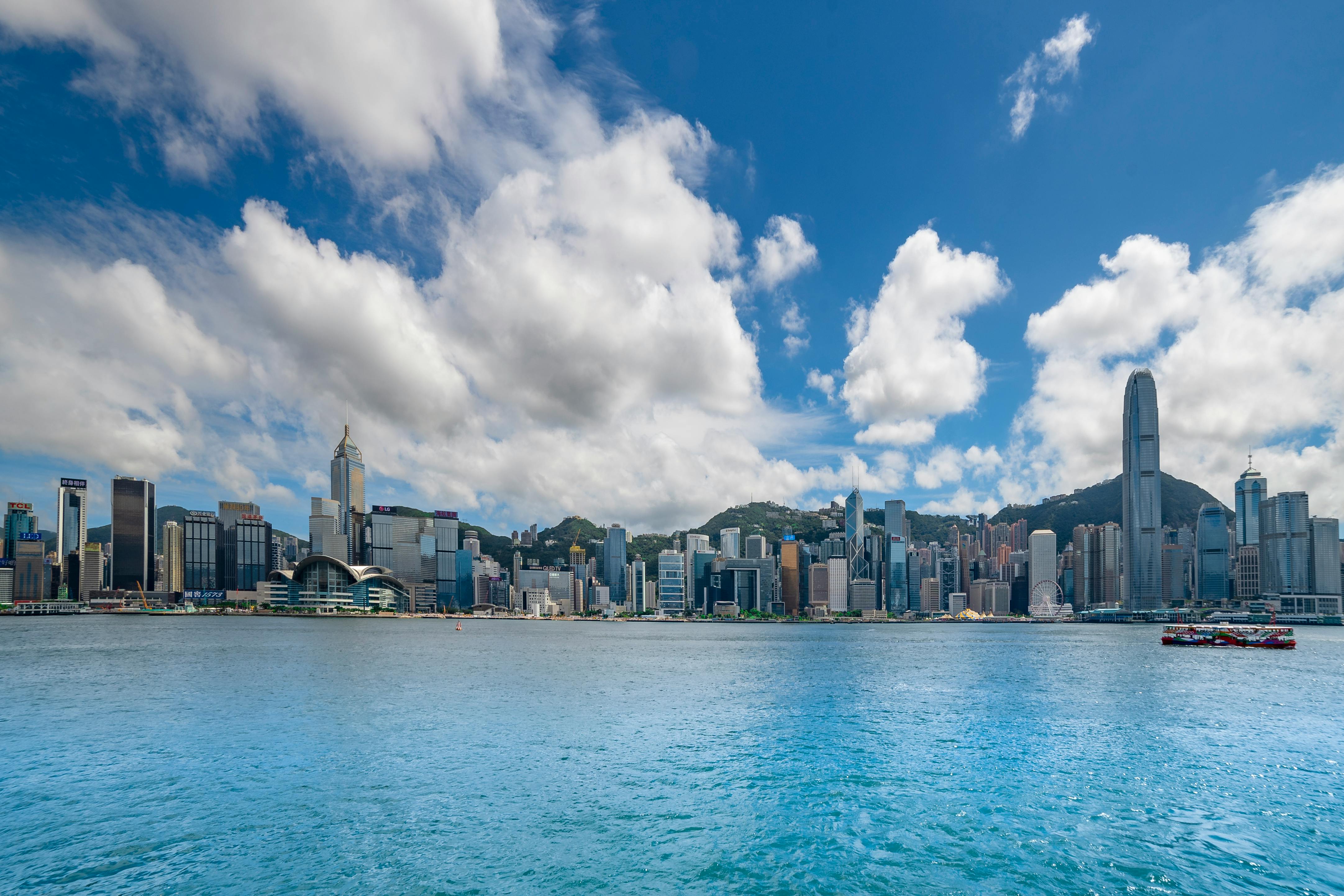 city buildings near body of water under blue sky and white clouds