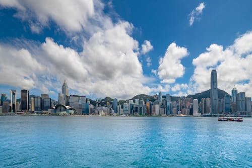 City Buildings Near Body of Water Under Blue Sky and White Clouds