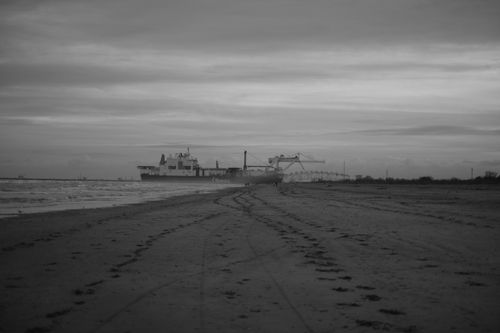 Free Monochrome view of a cargo ship on a foggy seashore with dramatic clouds. Stock Photo