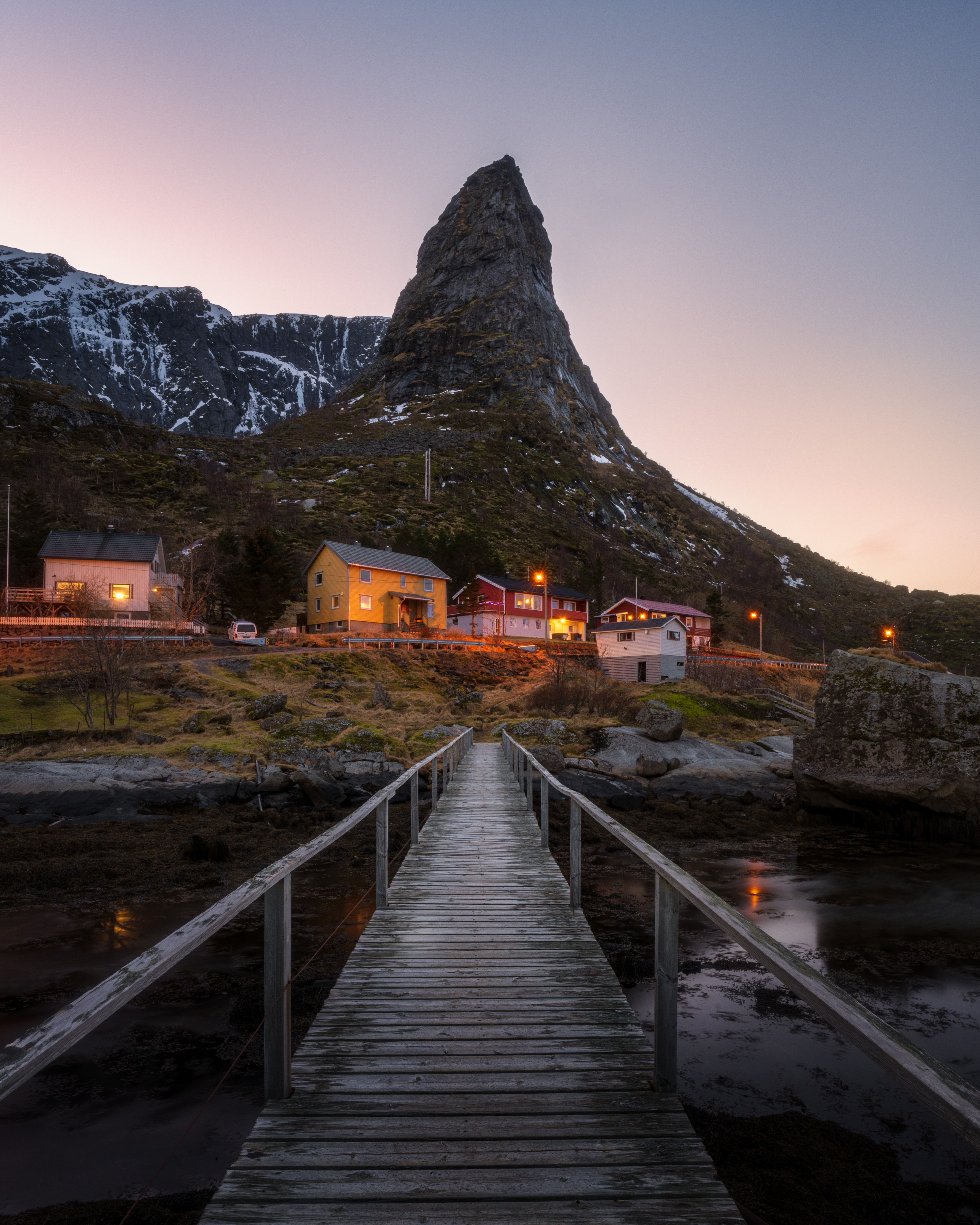 Discover the enchanting dusk landscape of Norway's Lofoten Islands with classic fishing cabins and dramatic peaks.