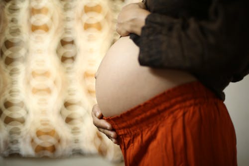 A Pregnant Woman in a Black Bodysuit Touching Her Belly · Free Stock Photo