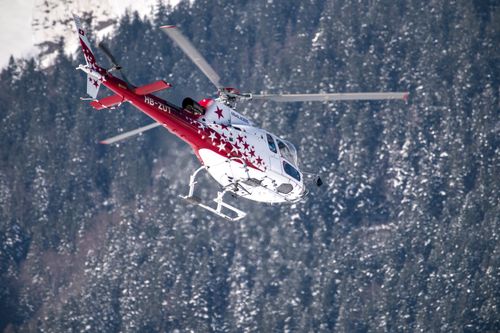 Free A helicopter flies over a winter forest in Switzerland, showcasing adventure. Stock Photo