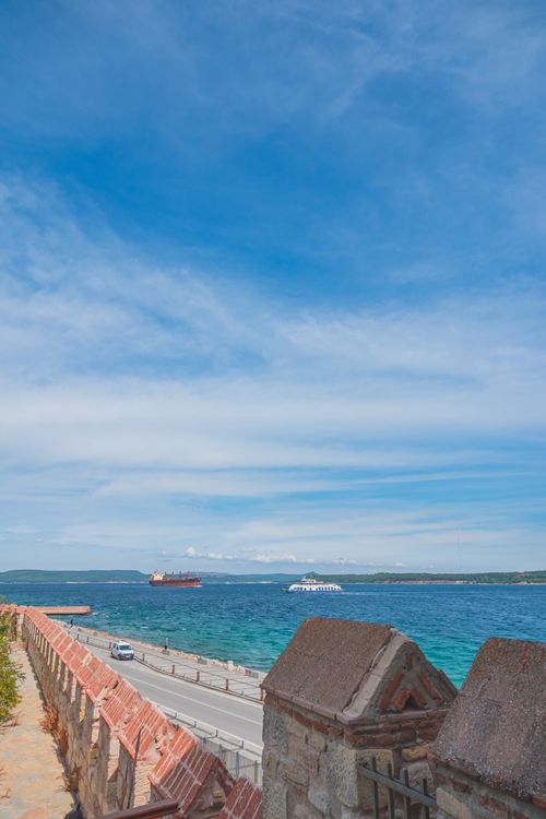 Free Vibrant seaside view with a road beside the blue ocean under a clear sky. Stock Photo