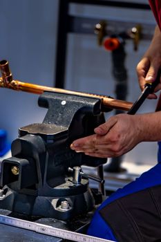 Plumber bending copper pipe with specialized equipment