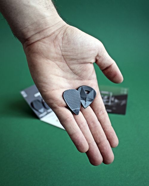 Free Detailed close-up of a hand holding textured guitar picks over a green surface, perfect for music-related themes. Stock Photo