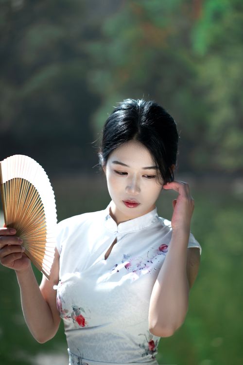 Free Portrait of a woman in traditional attire holding a fan outdoors. Stock Photo