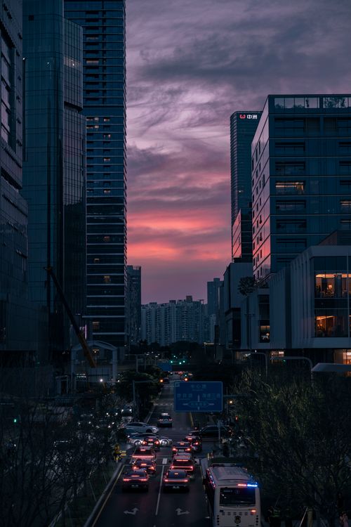 Free Cityscape at sunset with skyscrapers and busy street traffic under colorful sky. Stock Photo