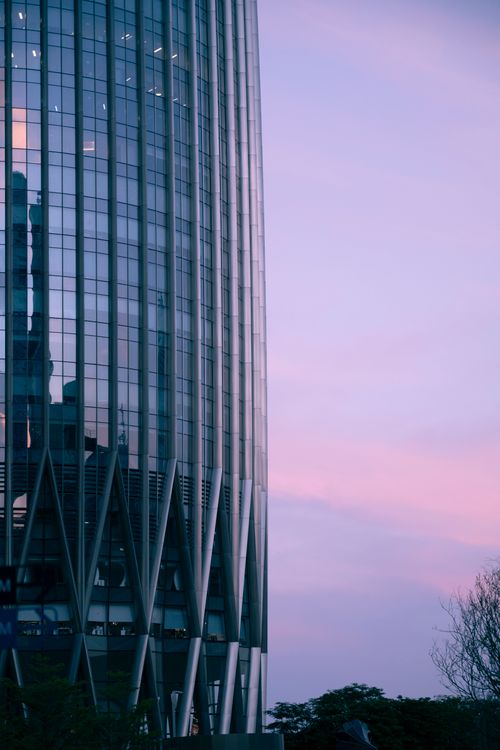 Free Glass skyscraper with sunset sky, showcasing modern architecture. Stock Photo