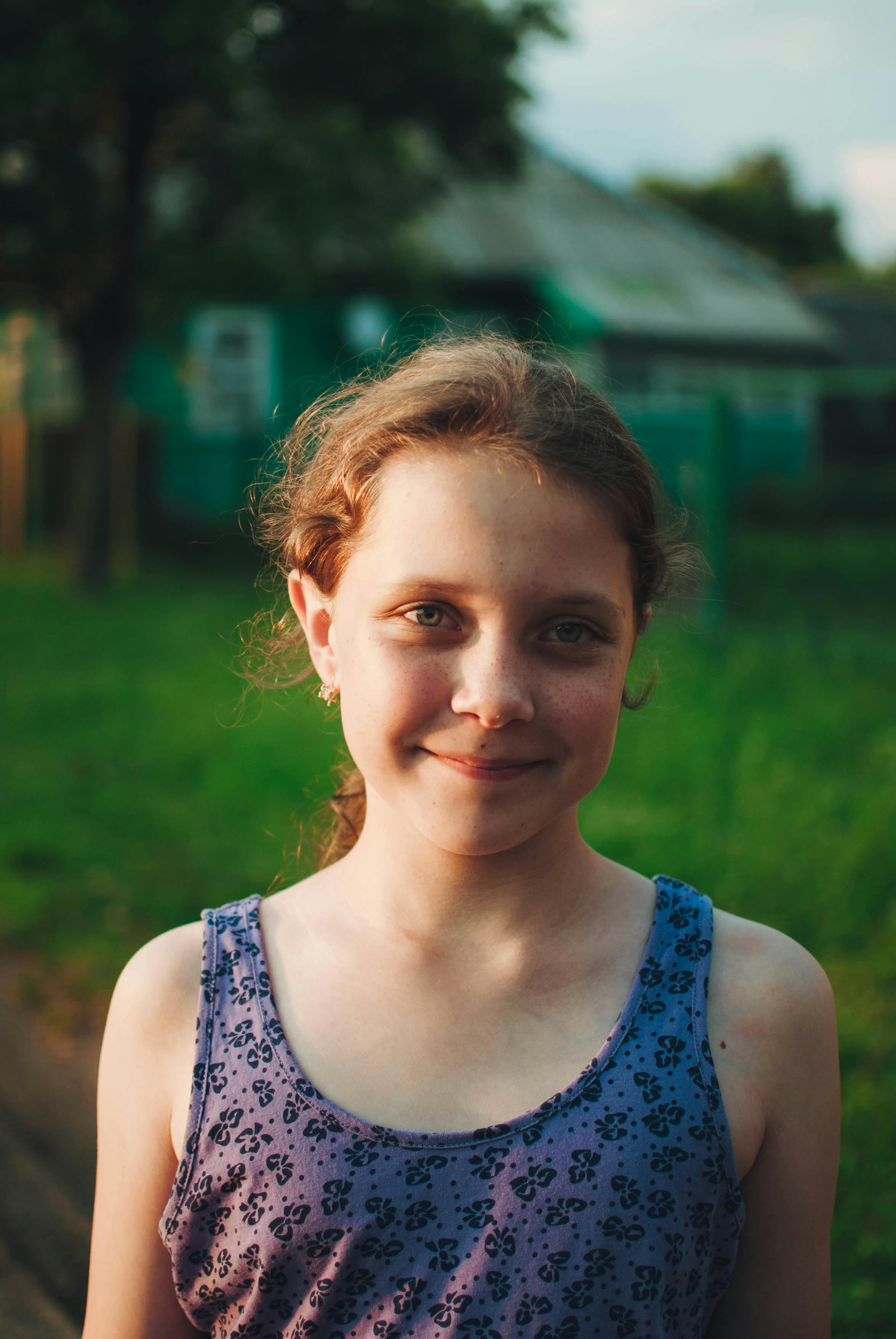 Portrait of a smiling girl outdoors under soft, evening summer light.