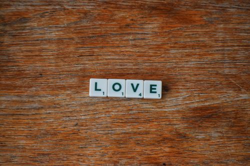 Free Scrabble tiles spell 'LOVE' on a rustic wooden surface, conveying a warm and heartfelt message. Stock Photo