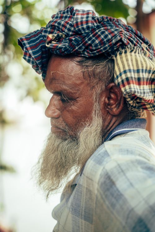 Free Close-up side portrait of an elderly man wearing traditional checkered headscarf outdoors. Stock Photo
