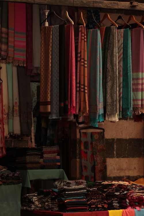 Free A variety of colorful scarves hanging in a traditional market setting, showcasing diverse patterns and textures. Stock Photo