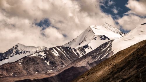 Free Stunning view of snow-capped mountains under a dramatic cloudy sky, showcasing natural beauty. Stock Photo