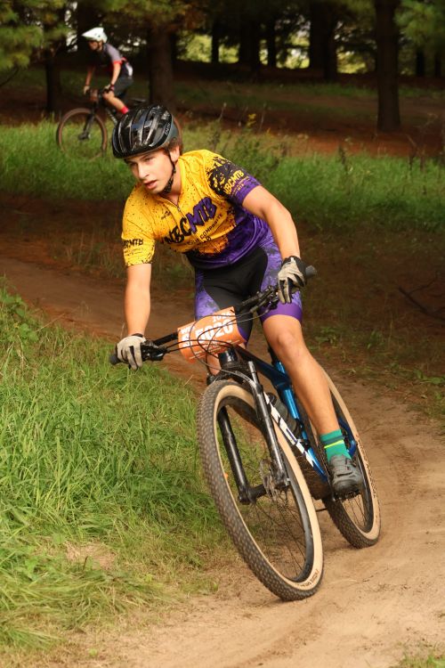 Free Teenager riding mountain bike on forest trail during race event. Stock Photo