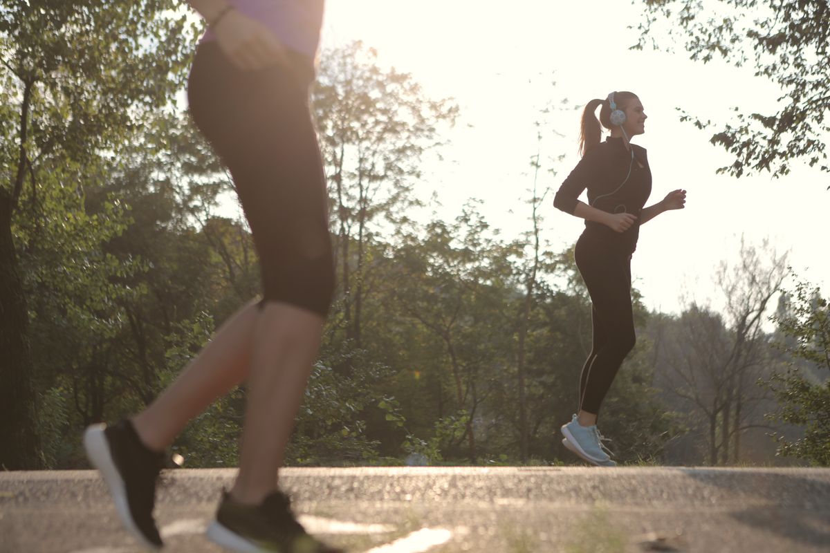 Two women jogging in a sunny park during a morning workout