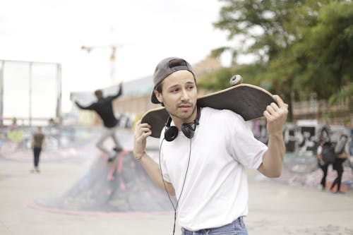Man in White Shirt and Blue Denim Jeans Holding Skateboard