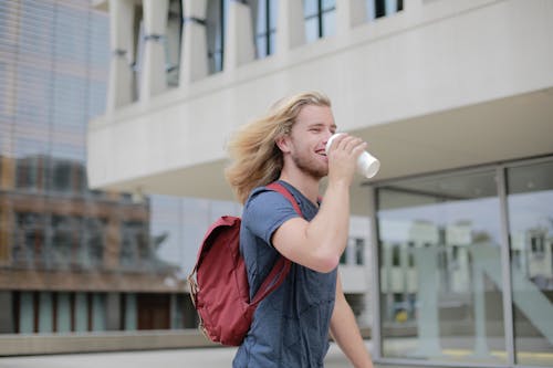 Man in Blue Shirt Drinking from White Cup