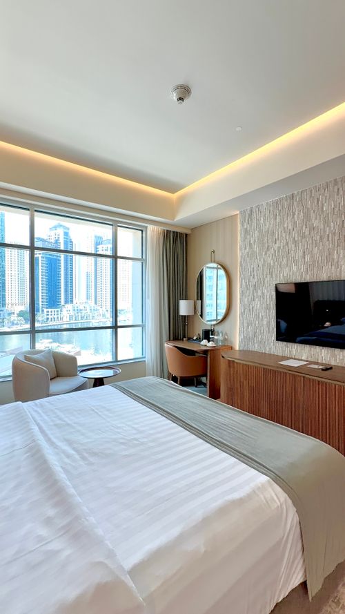 Free A spacious and bright hotel room with large windows overlooking a city skyline. Stock Photo