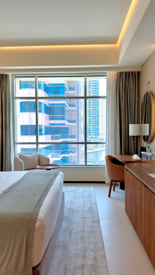 Free Chic hotel room featuring city skyline view through large window, modern decor. Stock Photo