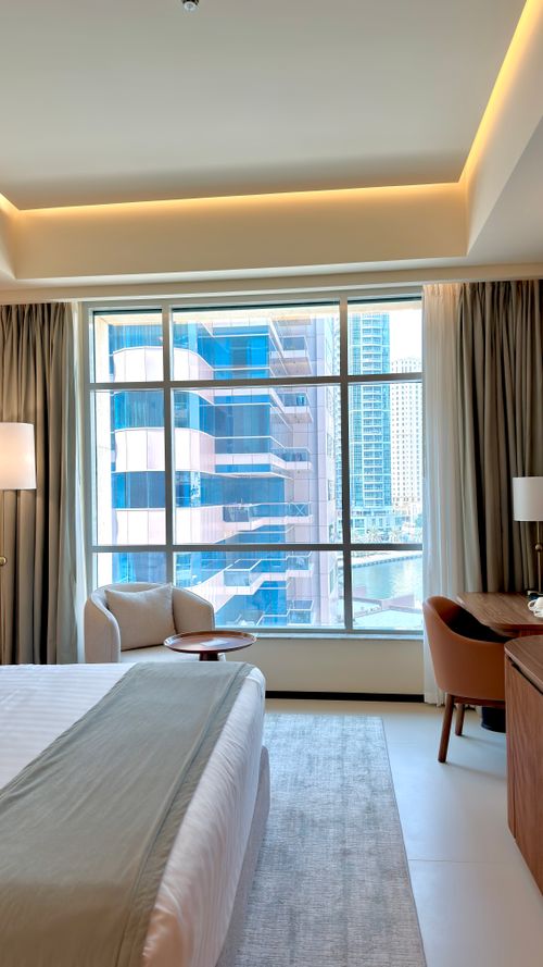 Free Bright modern hotel room interior with a large window showcasing a city view. Stock Photo