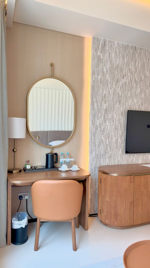 Free Sleek hotel room interior featuring a mirror, desk, chair, and TV. Elegant design with warm tones. Stock Photo