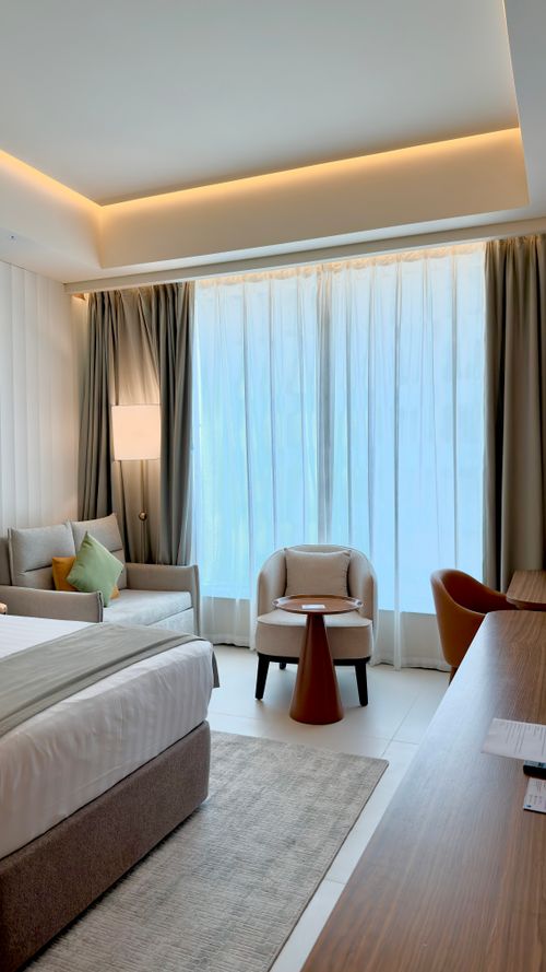 Free Serene and modern hotel room with large window, cozy furniture, and ambient lighting. Stock Photo