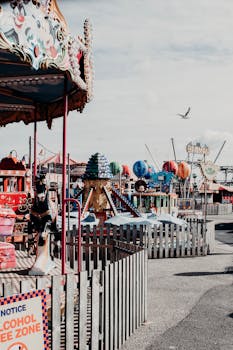 A lively amusement park scene featuring various rides and a carousel on a bright day.
