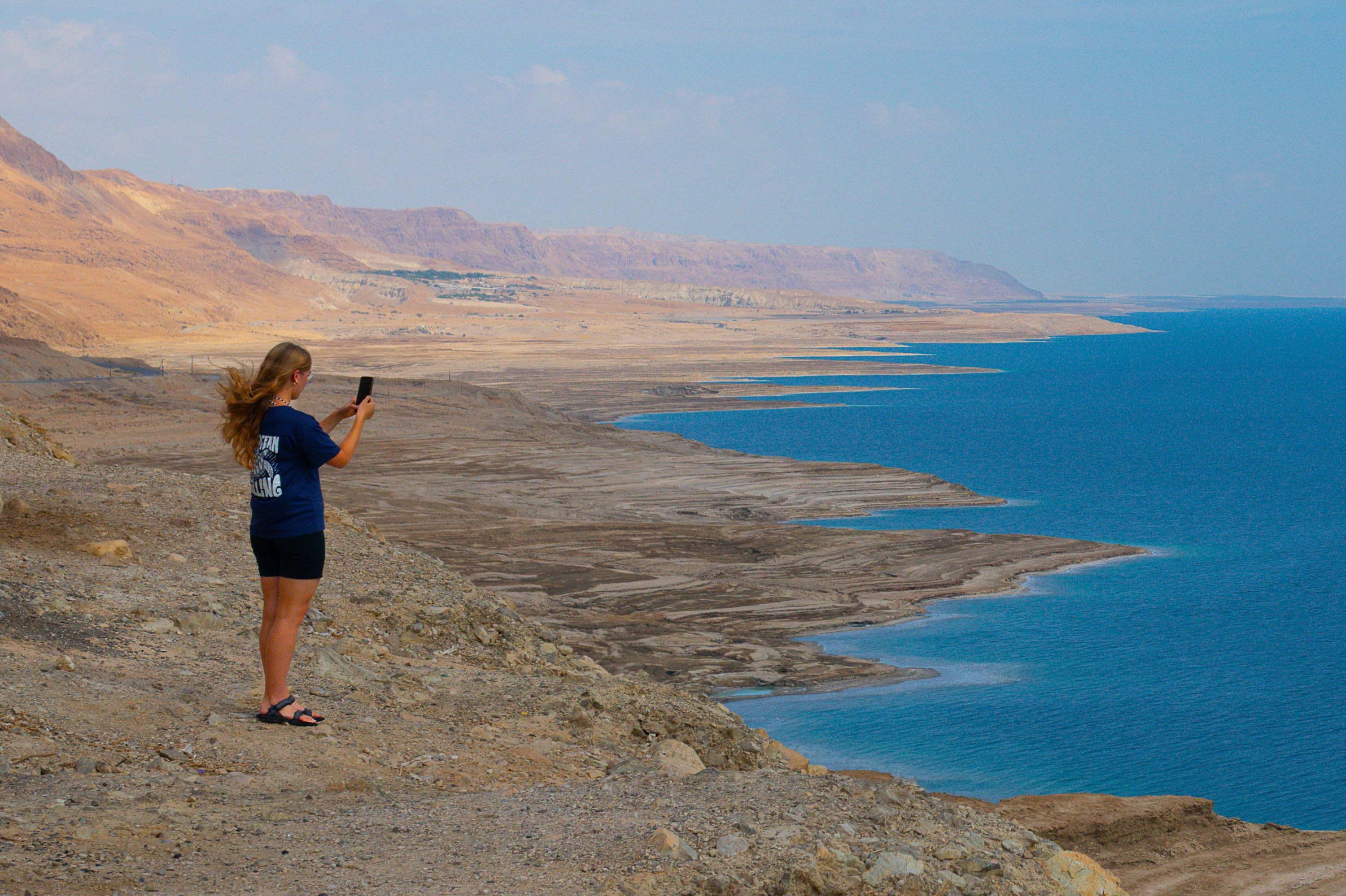 A tourist takes a photo of the breathtaking Dead Sea landscape on a sunny day.