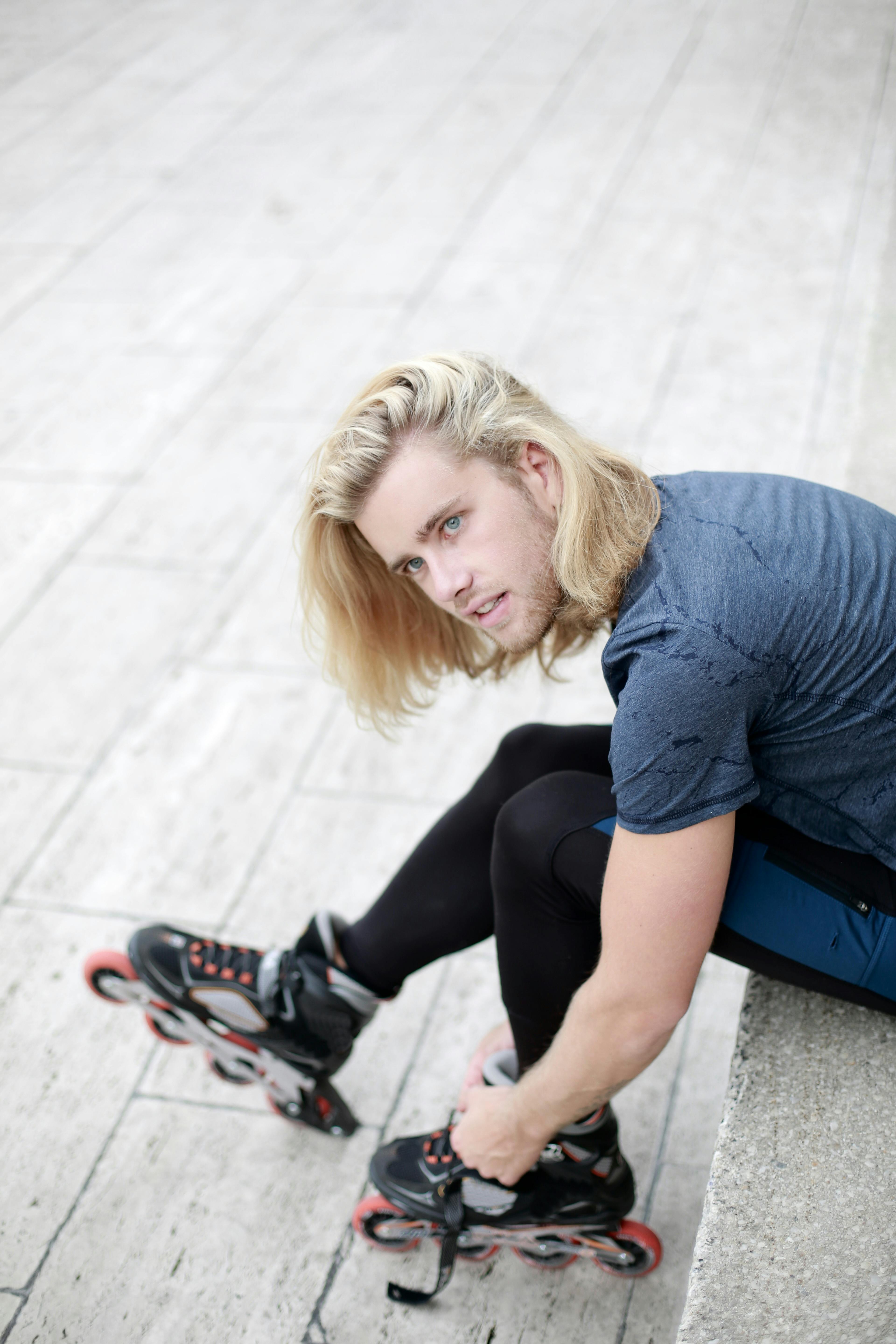 Blonde man tightening roller skates. Casual street style and leisure activity.