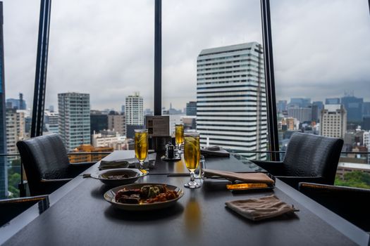 Chic dining setup in urban restaurant with stunning city skyline view.