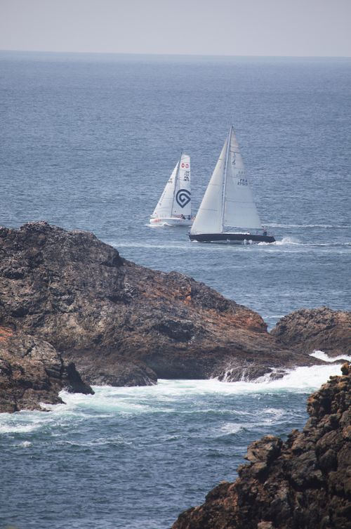 Free Two sailboats passing rocky shores under a clear sky in Brittany, France. Stock Photo