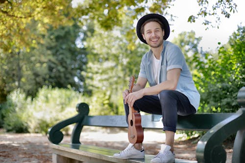 Man in Blue Crew Neck T-shirt and Black Pants Sitting on Wooden Bench