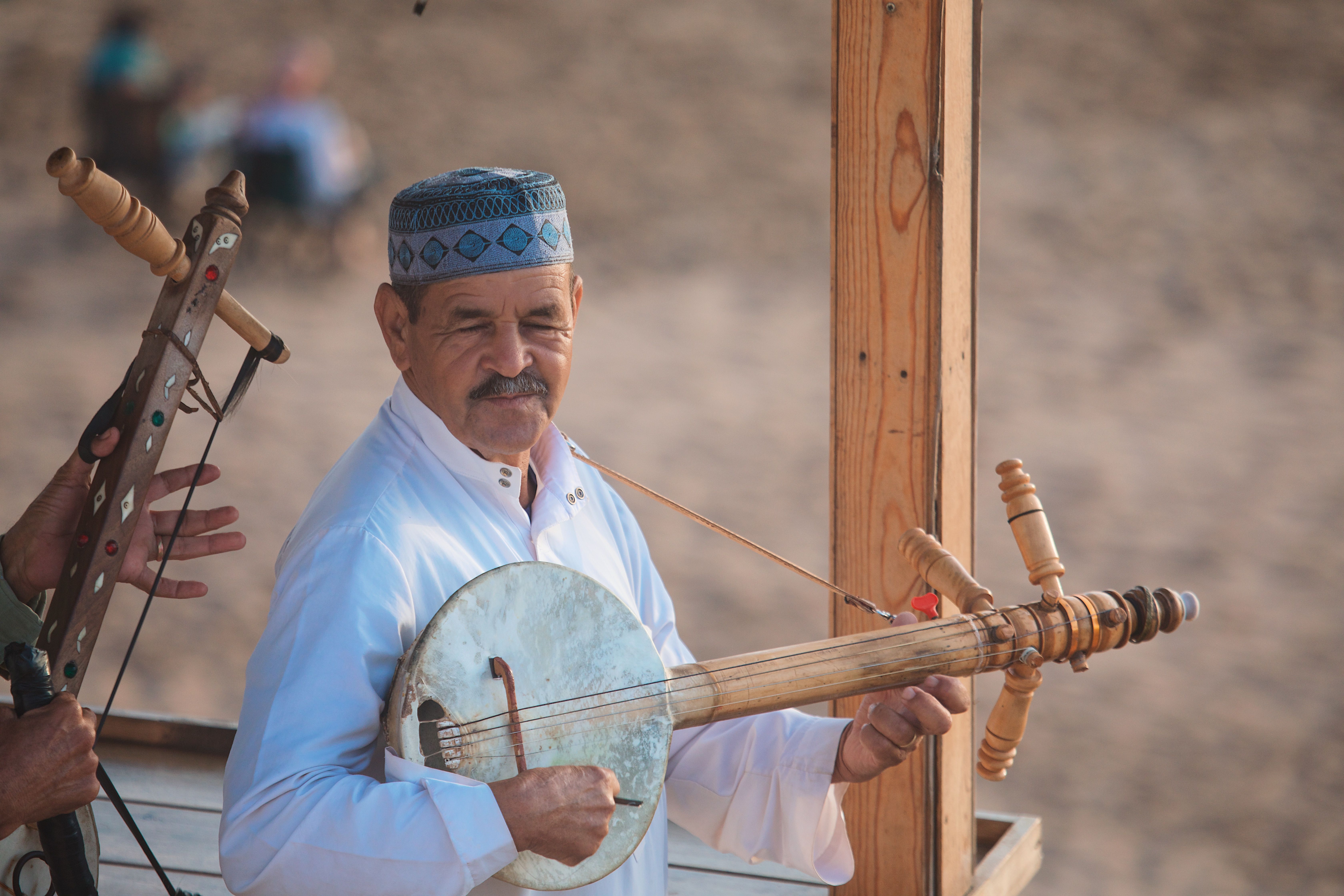 A traditional Moroccan musician plays a stringed instrument outdoors, showcasing cultural heritage.