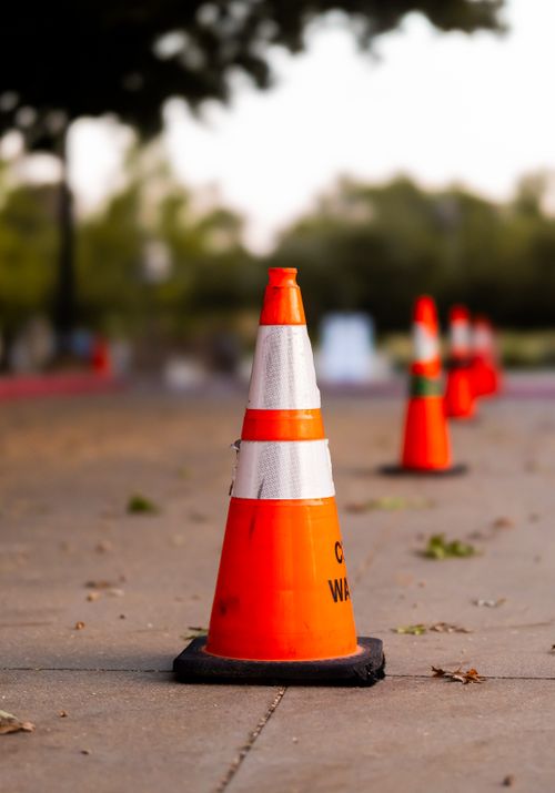 Free Line of orange traffic cones on a paved area outdoors, blurred background. Stock Photo