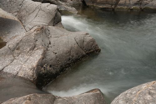 Free A tranquil stream gently flowing over smooth, weathered rocks in a natural setting. Stock Photo