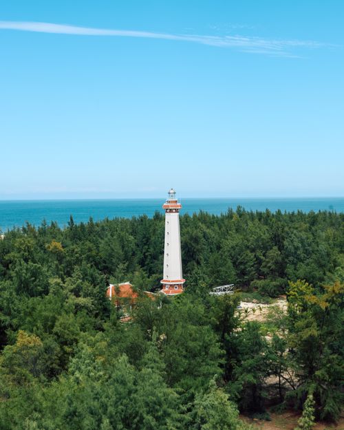 Free Aerial view of Long Chau Lighthouse surrounded by lush green forest and blue sea in Hue, Vietnam. Stock Photo