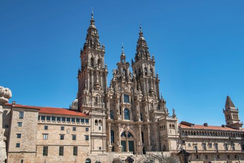 Free The grand facade of Santiago de Compostela Cathedral set against a vibrant blue sky, showcasing its stunning architecture. Stock Photo