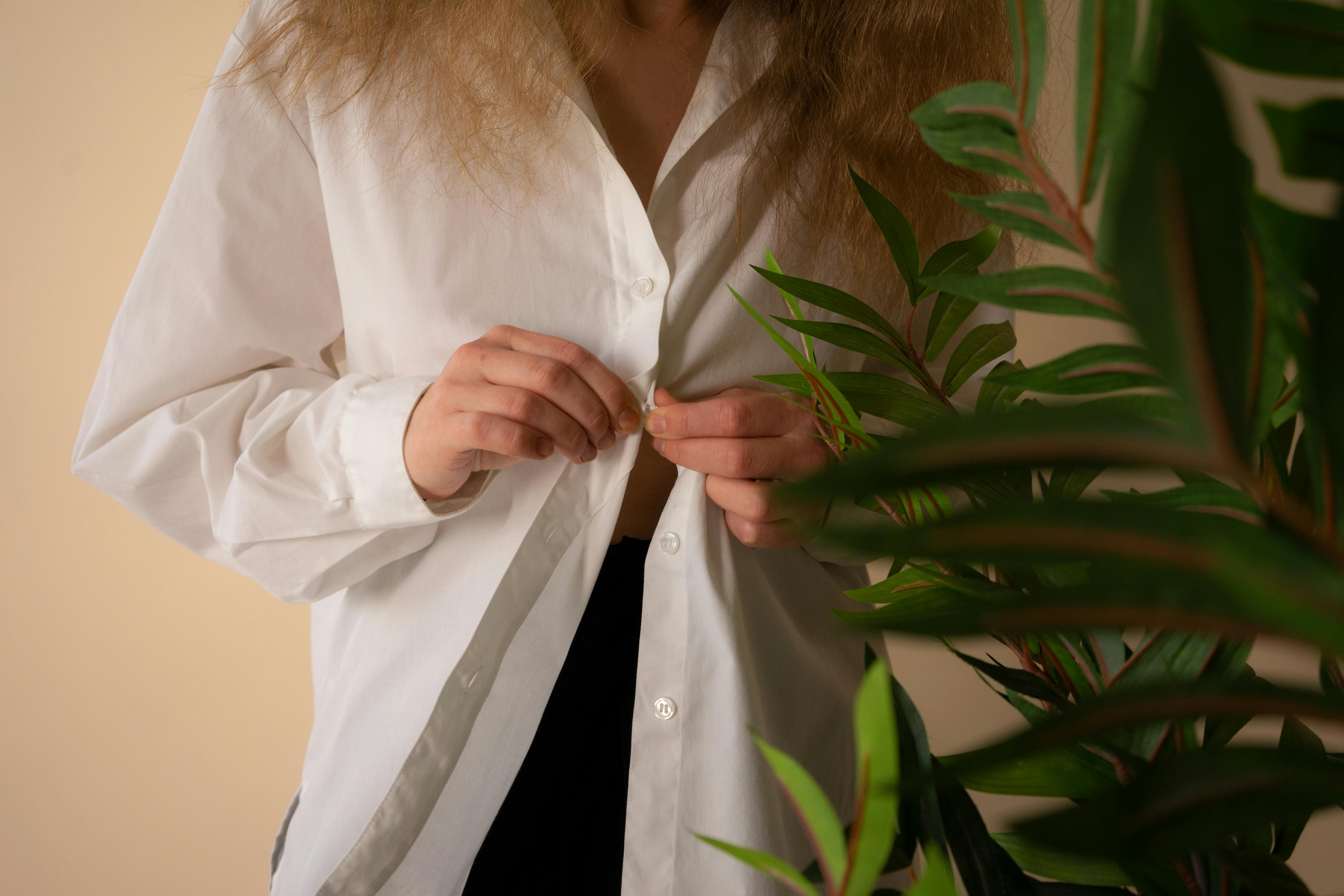 woman-in-white-button-up-long-sleeve-shirt-near-green-plant-free