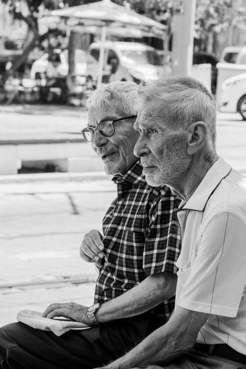 Free Black and white photo of two senior men sitting outdoors, enjoying each other's company. Stock Photo