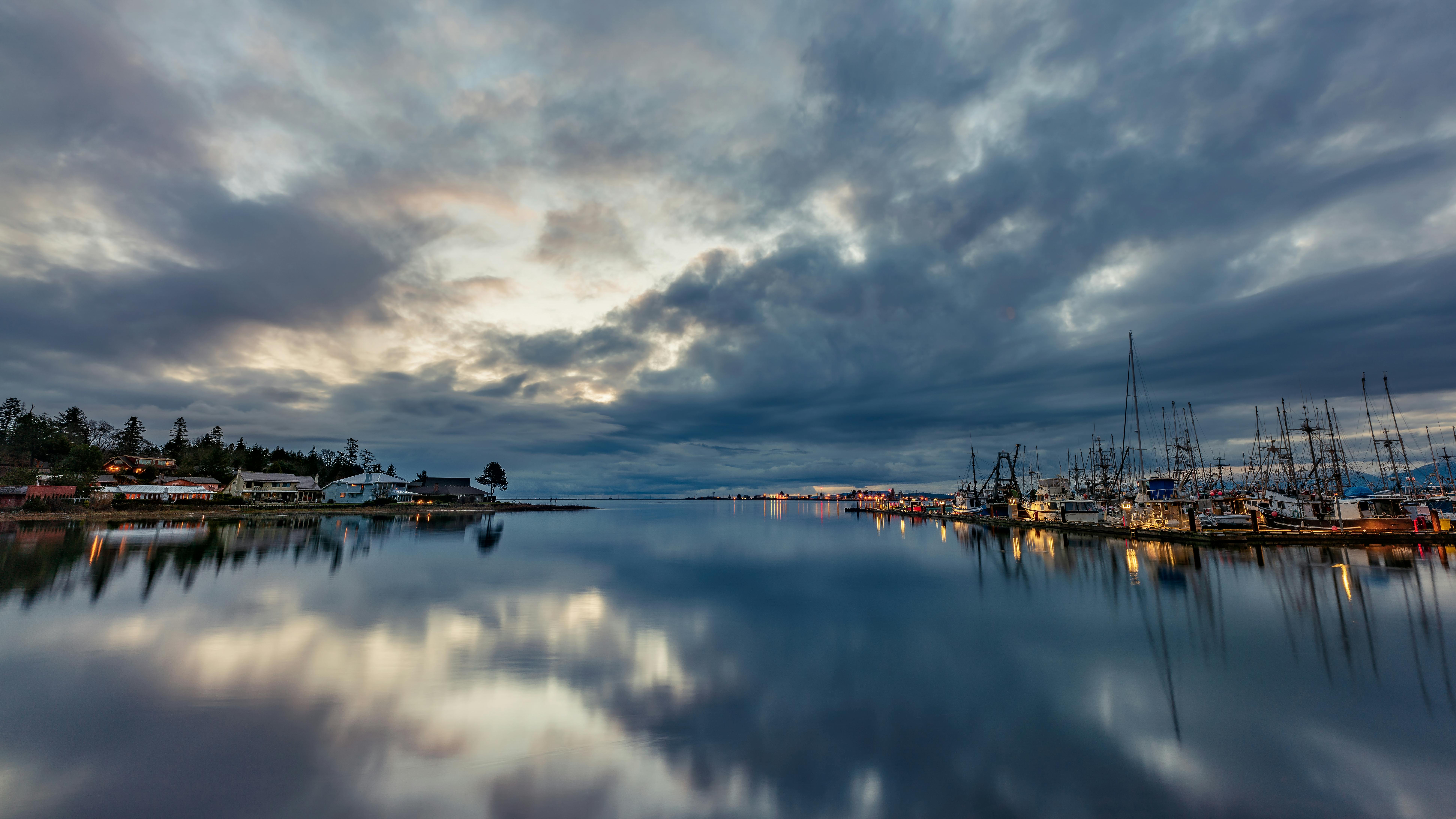 Free A tranquil view of Comox Fisherman's Wharf at dusk, with calm waters and cloudy skies. Stock Photo